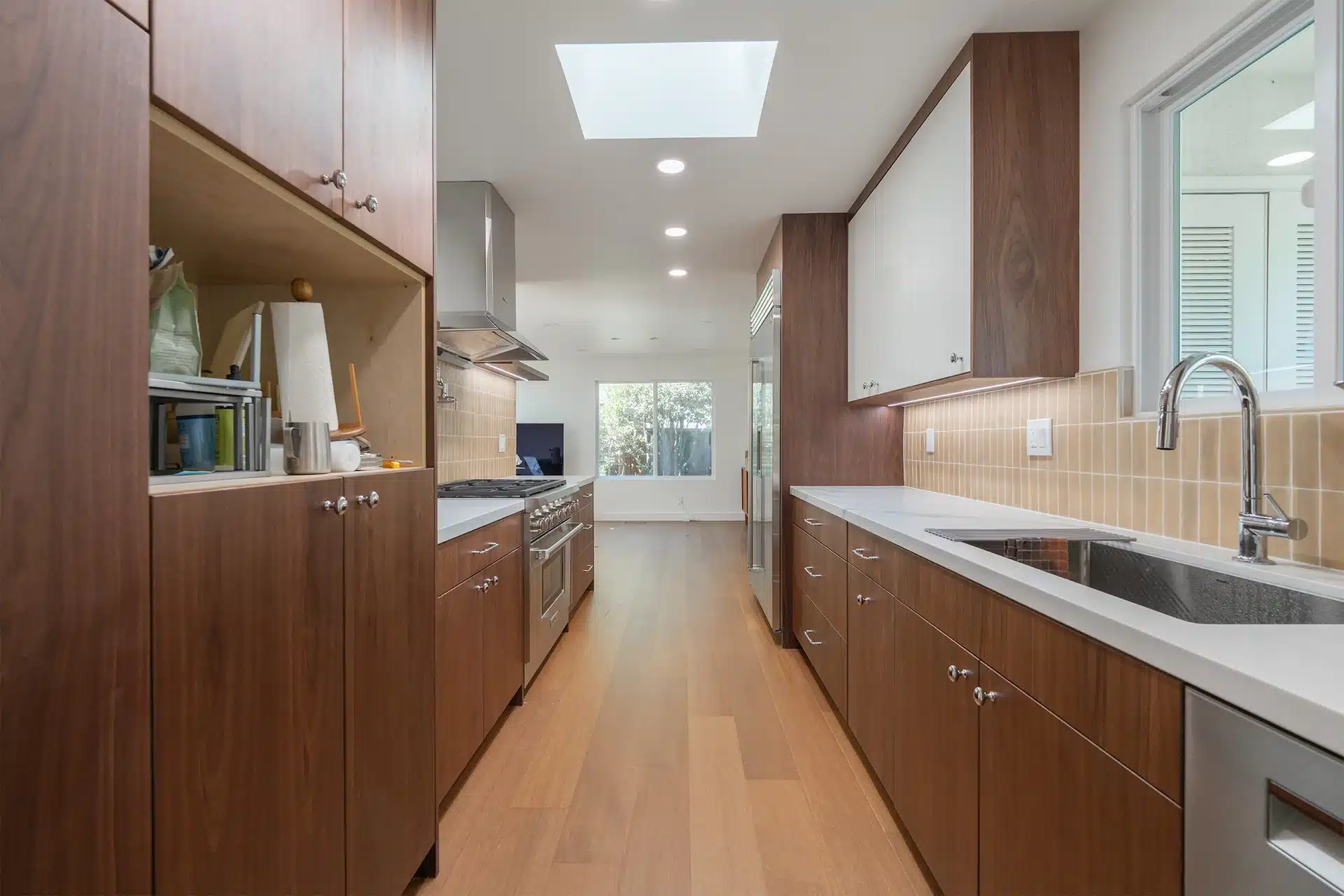 Walnut galley kitchen cabinetry running the length of the room